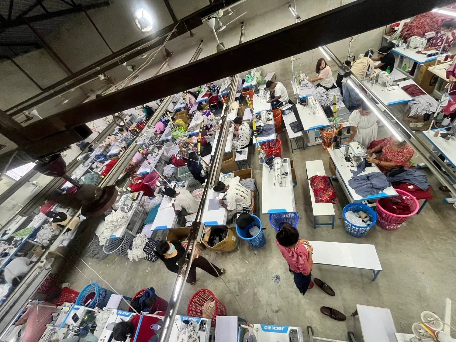 Die Nähhalle von Trishakti Apparel in Gaindakot, Nepal, von oben, mit Reihen von Maschinen und Näherinnen und Nähern