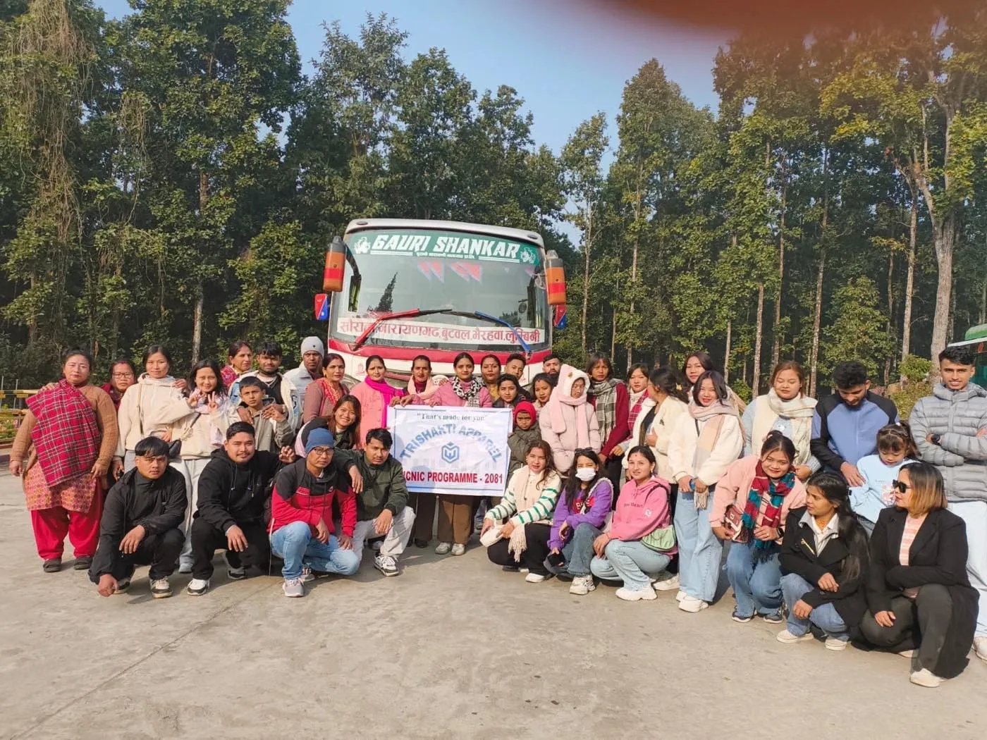 Das Team von Trishakti Apparel mit dem Picknick-Banner vor dem Einsteigen in den Bus
