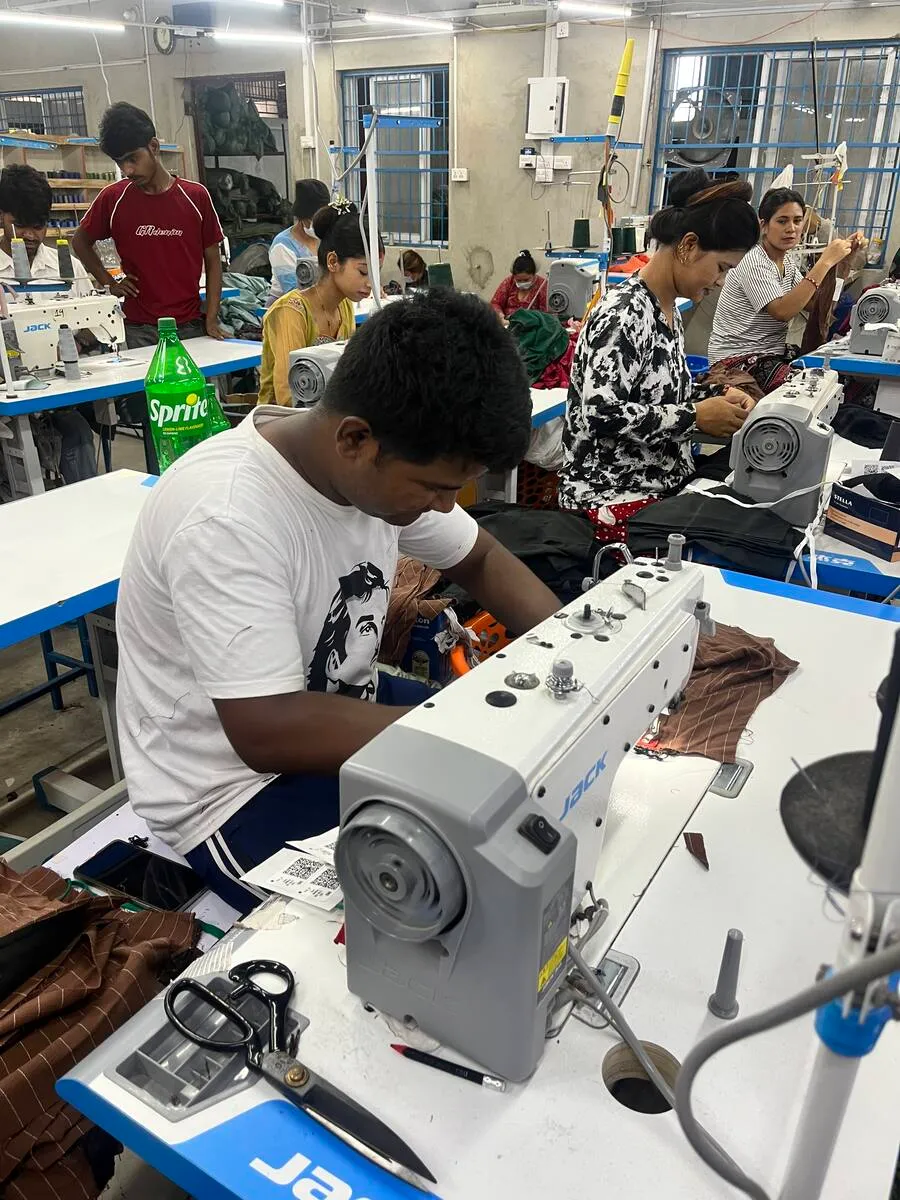 A machine operator sewing at a JACK industrial lockstitch machine on the Trishakti Apparel floor in Gaindakot, Nepal