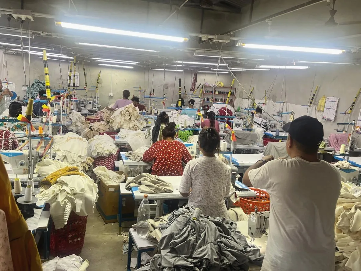 गैंडाकोट में Trishakti Apparel के सिलाई फ़्लोर पर अपनी मशीनों पर काम करते ऑपरेटर